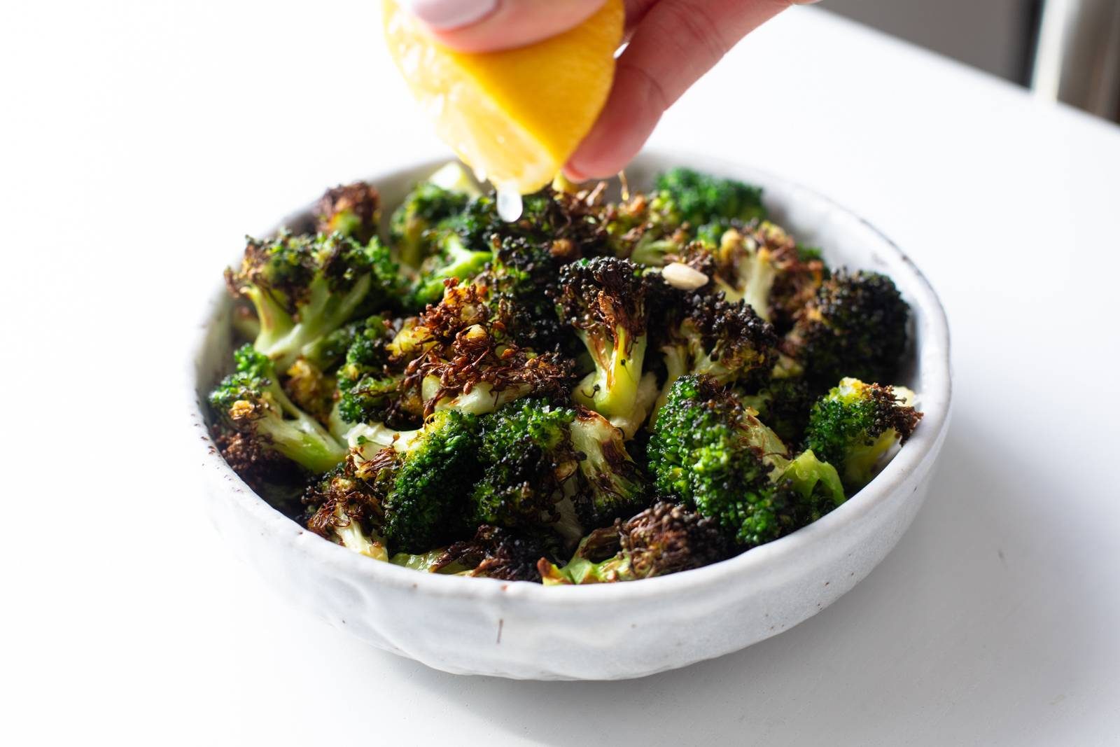 Squeezing lemon on top of air-fried broccoli.