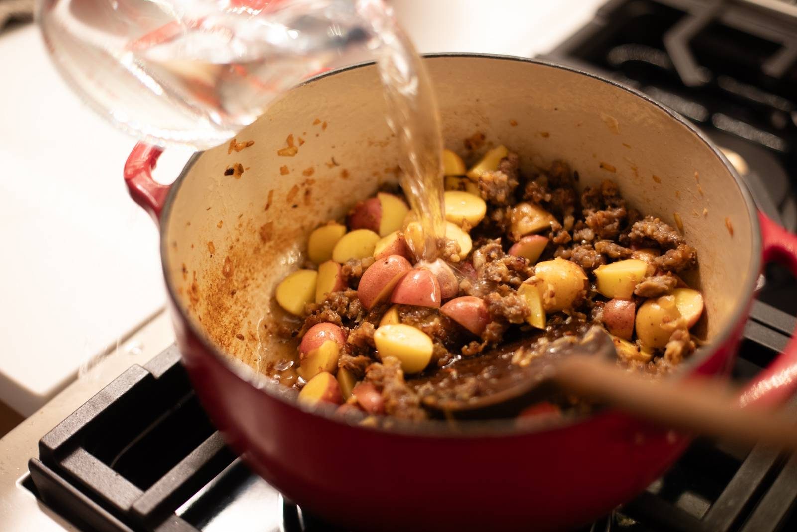 Adding potatoes and water/broth to the pot.