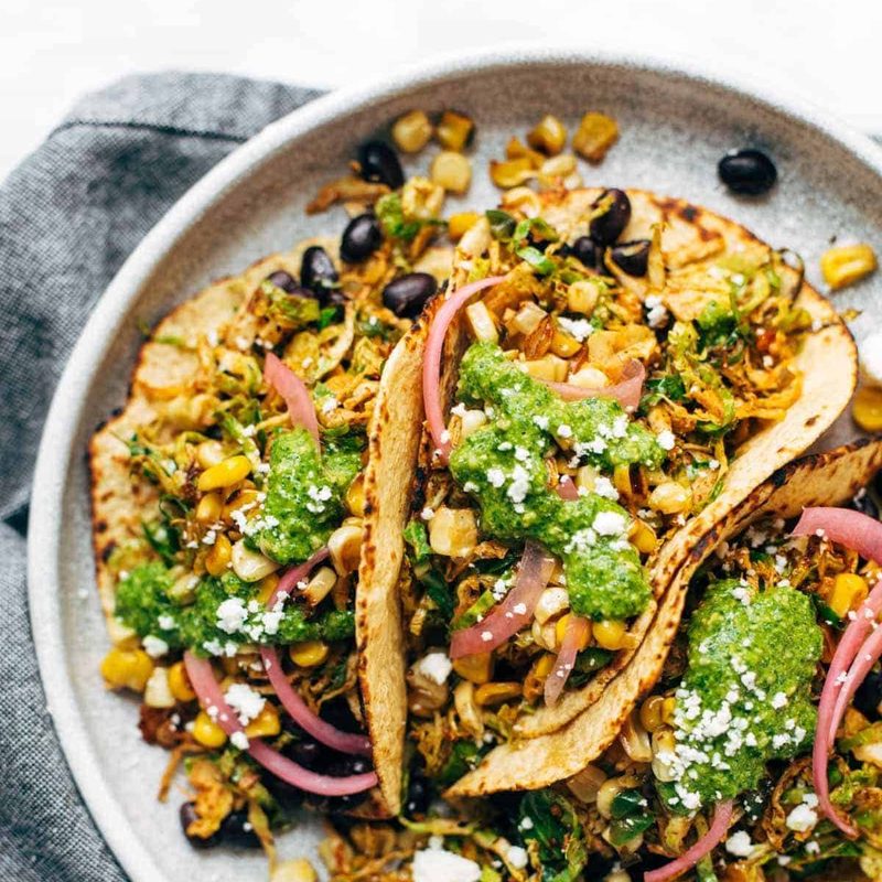 Brussels sprouts tacos on plate with toppings.