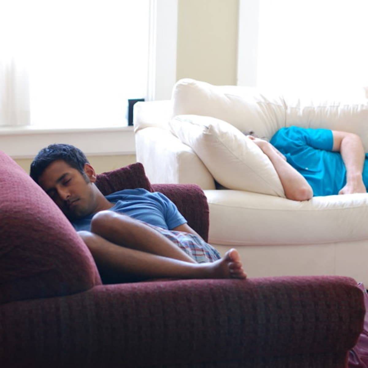 Two men sleeping on couches.
