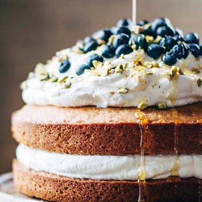 Blueberry Orange Brunch Cake on a cake stand with agave poured on it.