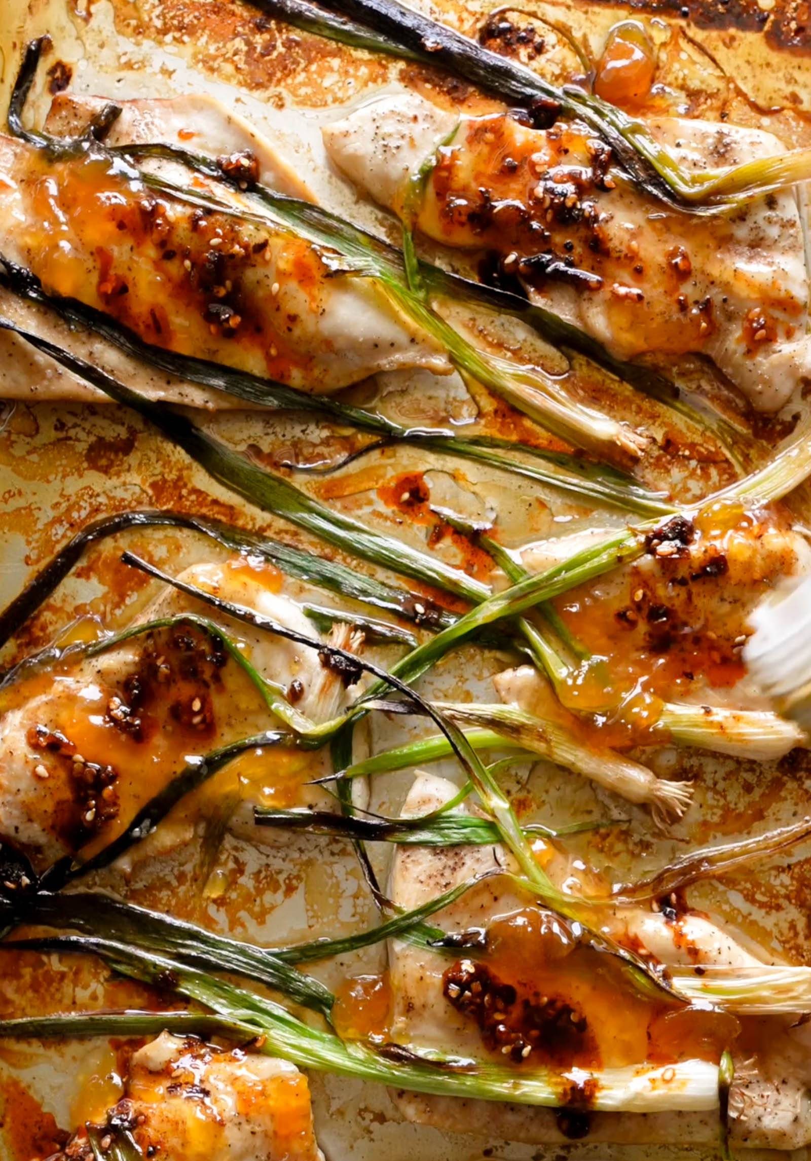 Apricot chicken on a sheet pan with charred scallions on top.