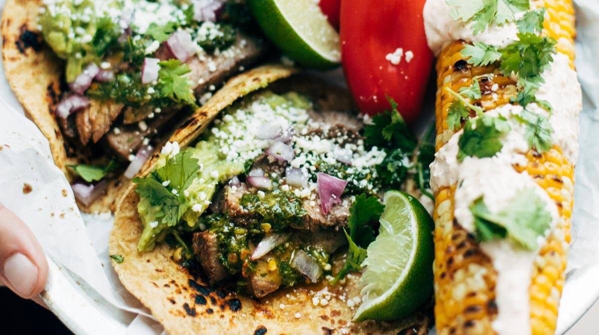Steak Tacos on plates with hand squeezing a lime.