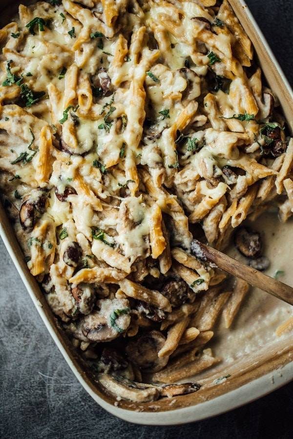 Healthy Mushroom Alfredo Pasta Bake in a dish with a wooden spoon.
