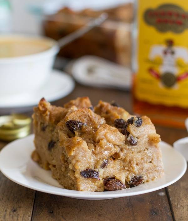 Bread pudding with hot butter rum sauce on a white plate.