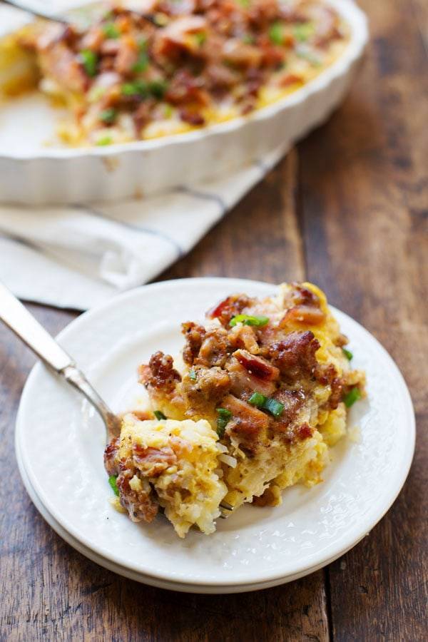 One piece of Ham and Sausage Hash Brown Egg Bake on a white plate with a fork.