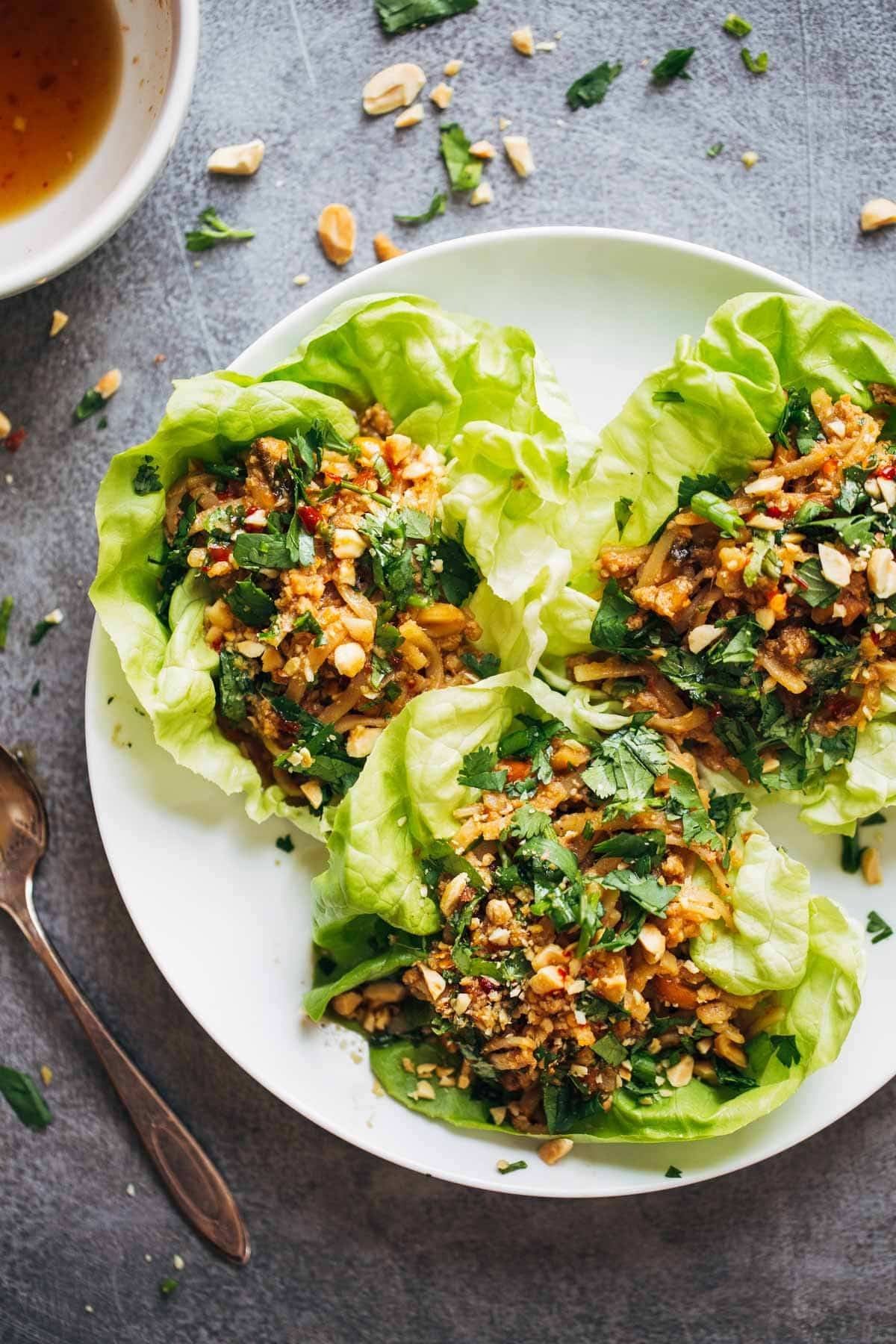 Peanut Chicken Lettuce Wraps with a Ginger Garlic sauce on a white plate.