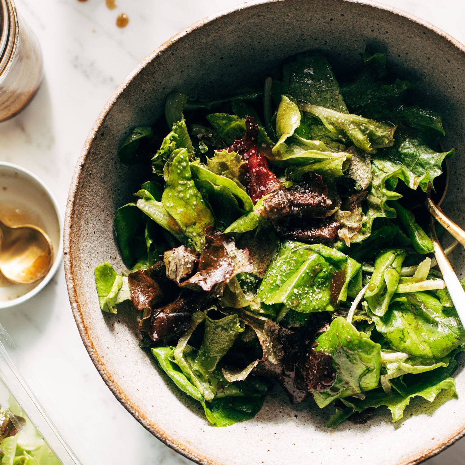 Green salad in a bowl with dressing on the side.