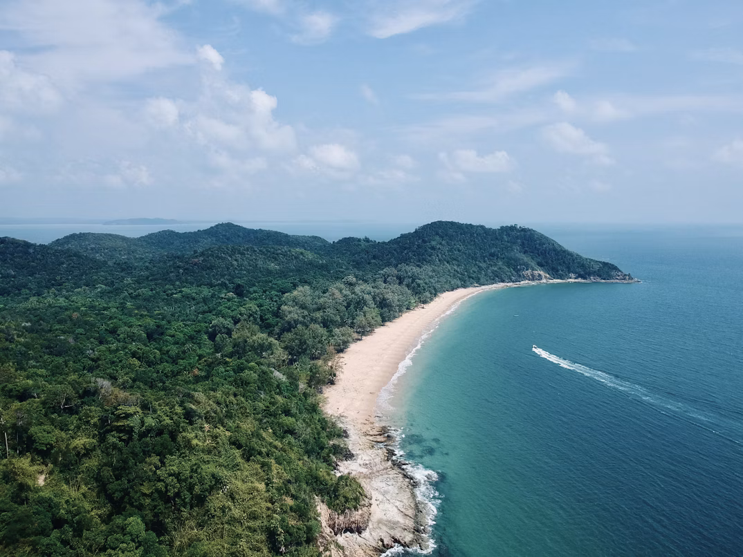 Peaceful Malaysian coastline during shoulder season with gentle waves and soft sunlight
